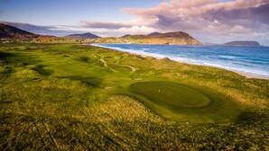 A golf course with a view of the ocean and mountains in the background.