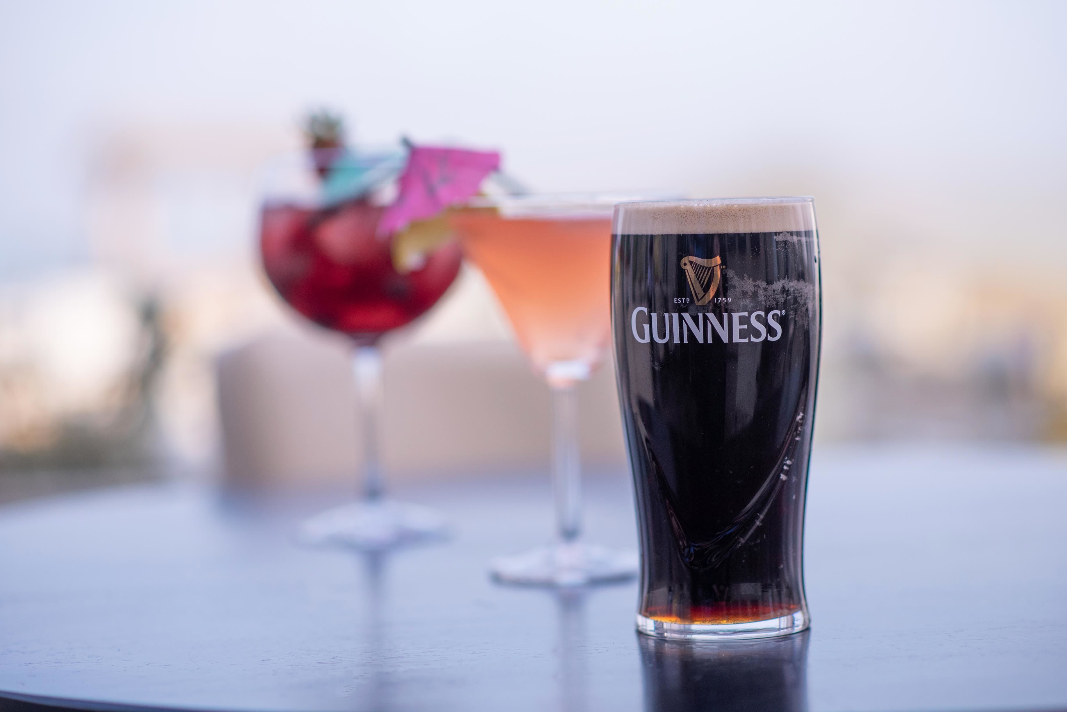 Um copo de Guinness sobre uma mesa, com fundo desfocado.