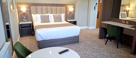 Una habitación de hotel con cama, lámparas de noche, un escritorio, una silla y una mesa redonda.