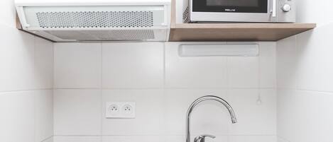 A kitchen with a microwave, stove, sink, and wooden cabinet.