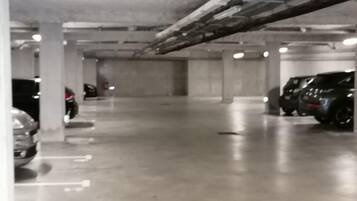 Un parking à plusieurs niveaux, avec des piliers en béton et quelques voitures garées.
