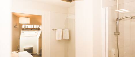 Un baño moderno con cabina de ducha de vidrio, un espejo y tocador de madera.