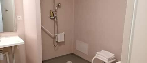 Un baño pequeño con lavamanos, ducha, inodoro y un cubo de basura.