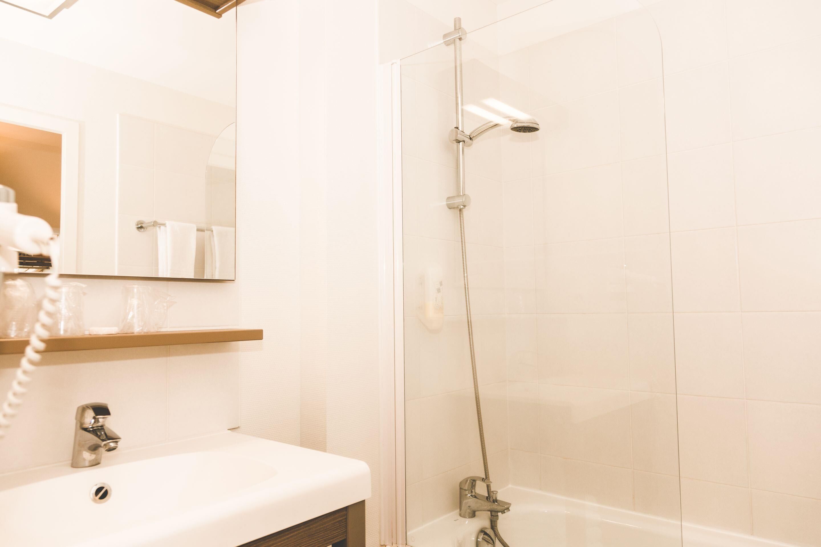 A bathroom with a sink, mirror, and shower.