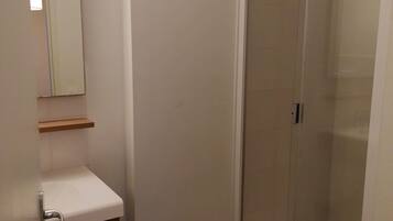A bathroom with a white sink, mirror, and a glass shower enclosure.