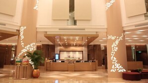 Eine großzügige Lobby mit einer Rezeption, einem großen Bildschirm und einem modernen Design mit geometrischen Mustern an den Wänden.