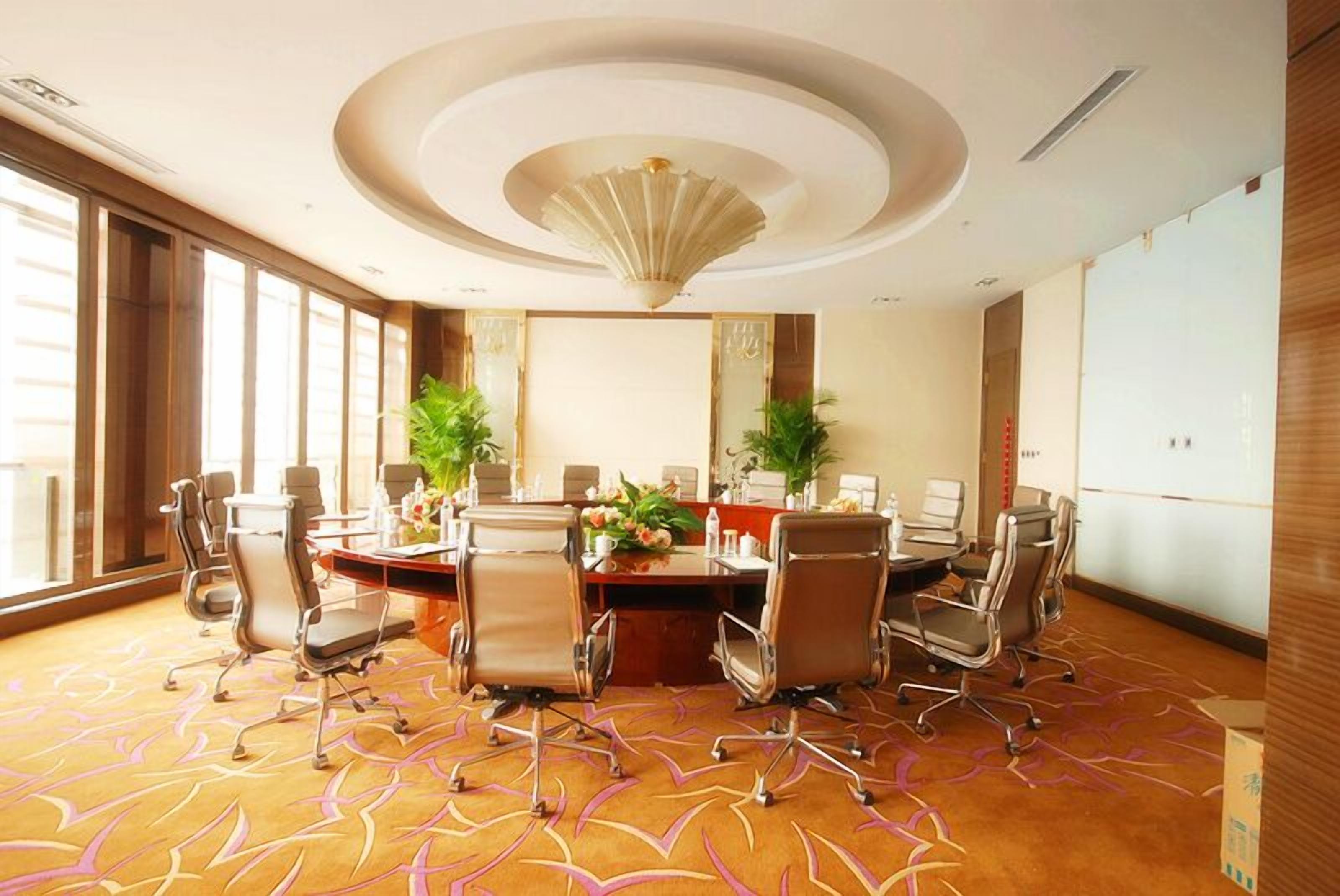 A conference room with a round table, multiple chairs, and a large window.
