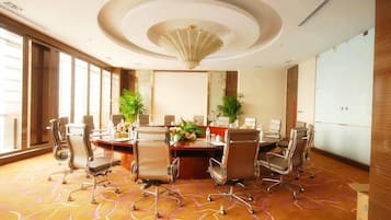 A conference room with a round table, multiple chairs, and a large window.
