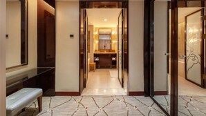 A hallway leading to a bathroom with a bench, a mirror, and a door with a decorative glass panel. - Inzone Garland Hotel Jinan (Jinan)