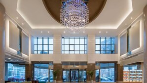 A spacious lobby with a high ceiling, large windows, and a modern chandelier. - Inzone Garland Hotel Jinan (Jinan)