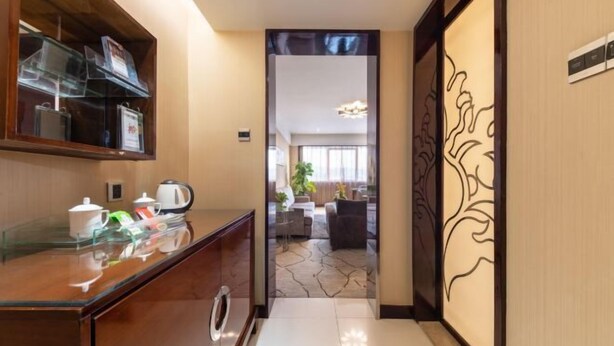 Hall d'albergo con reception, angolo caffè e vista su un'area relax con divano e pianta.