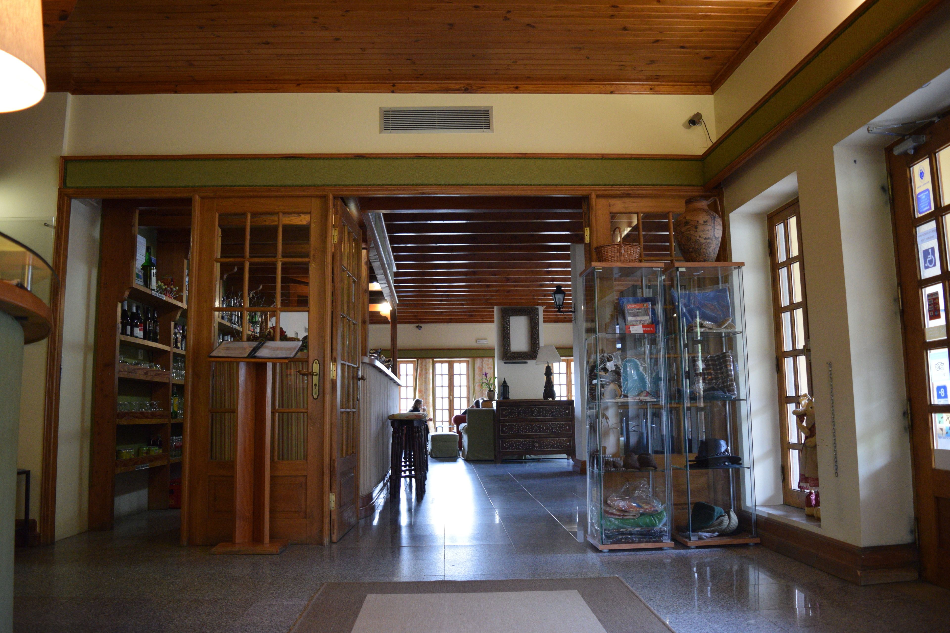 A spacious lobby with wooden flooring, a central staircase, and a glass display case with various items.