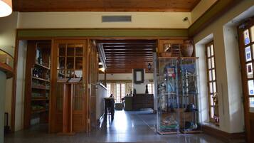 A spacious lobby with wooden flooring, a central staircase, and a glass display case with various items.