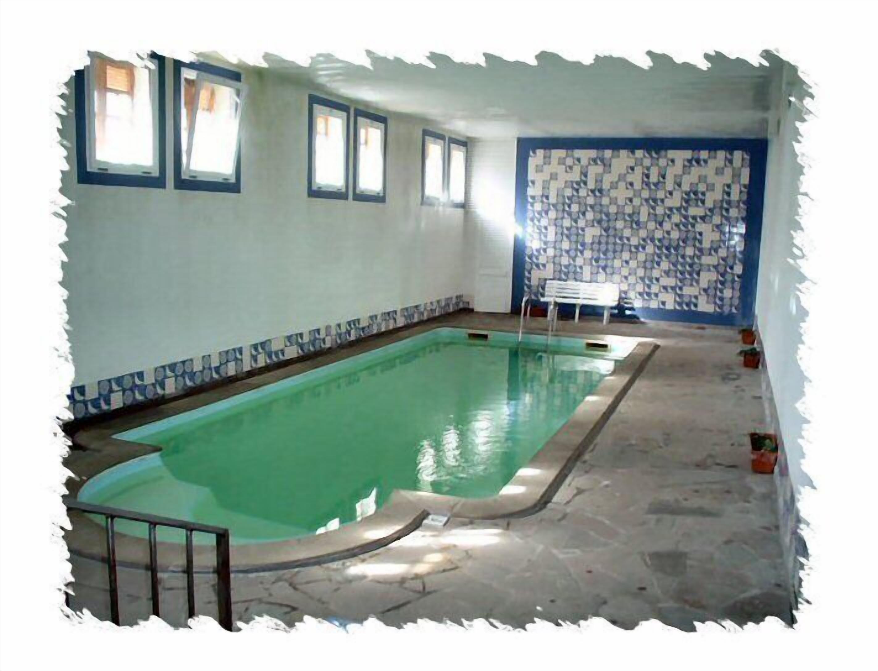 A swimming pool with a tiled border, a bench, and a patterned wall.