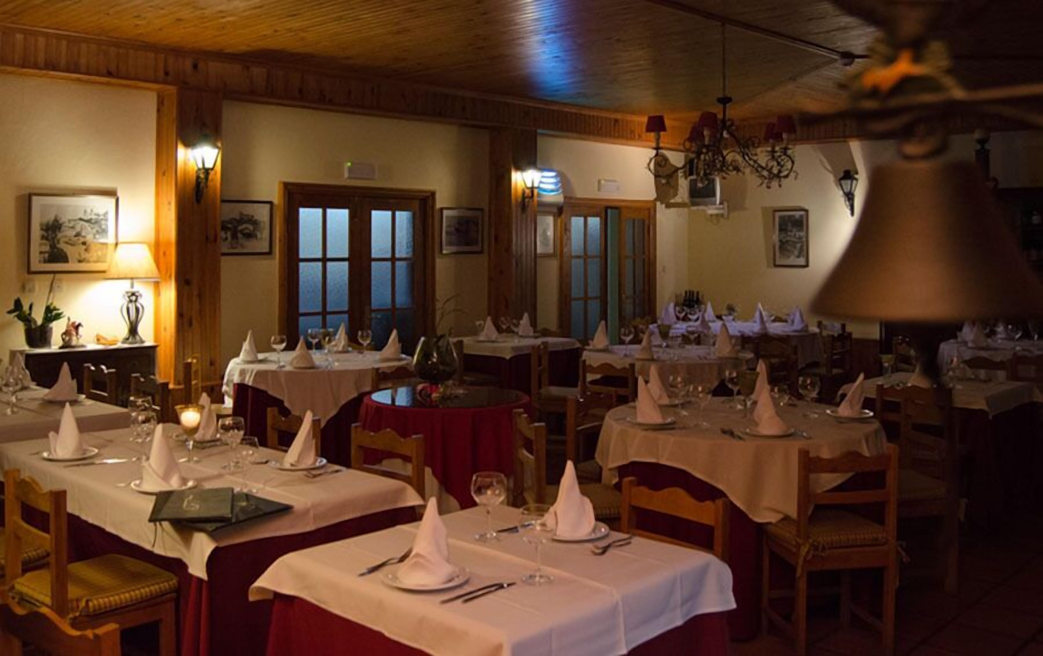 Un restaurant avec de nombreuses tables dressées pour le service, avec des nappes et des serviettes blanches.