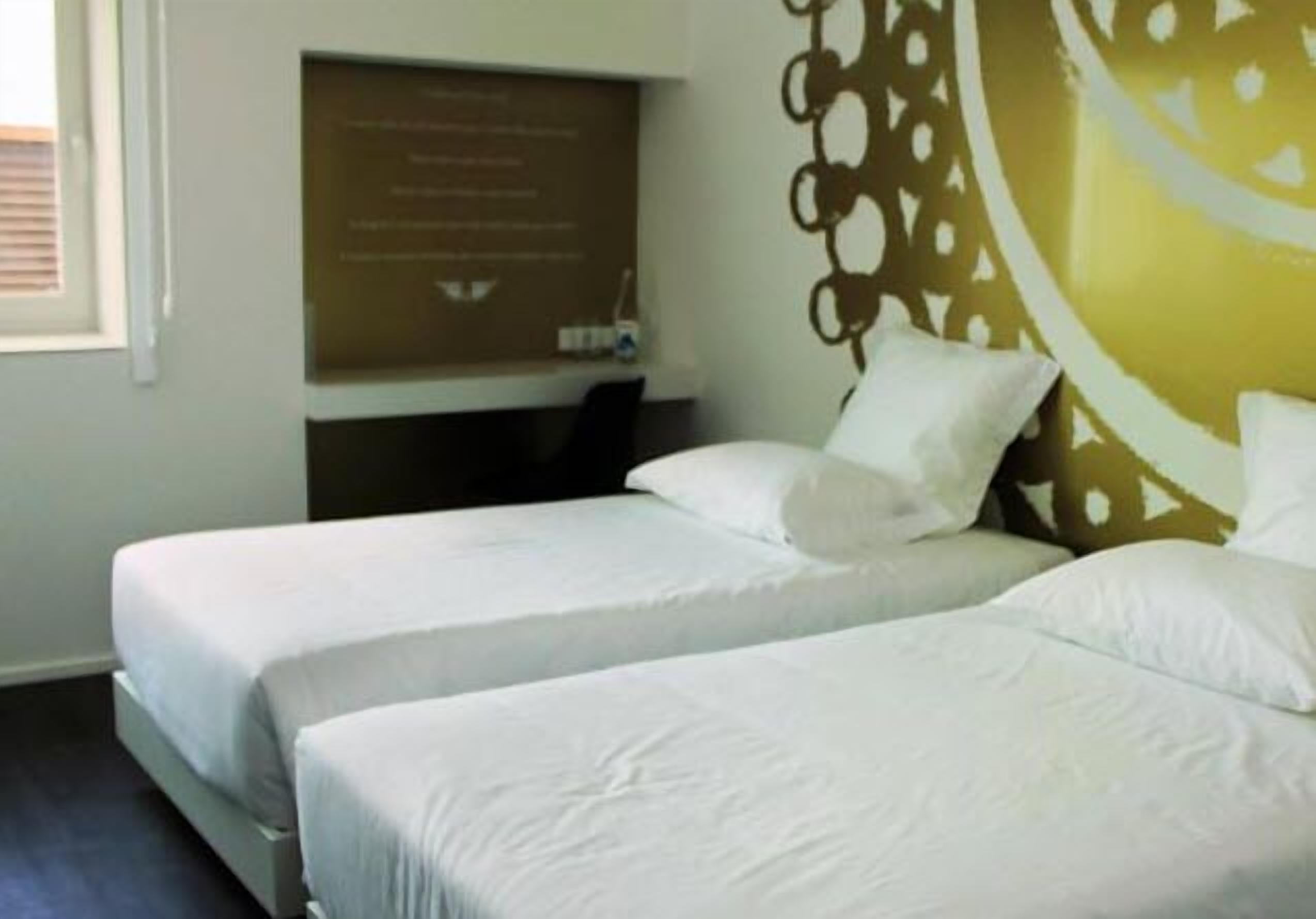 A hotel room with two beds, a wall-mounted information board, and a decorative wall panel.