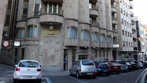 Un hotel de varios pisos con una fachada curva distintiva, múltiples balcones y un cartel que indica que es un albergue.