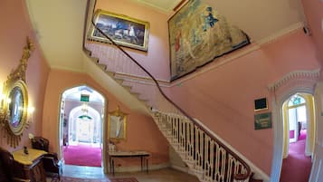 Un amplio pasillo con una escalera, un cuadro grande y un letrero que indica la ubicación de las habitaciones Lavaburn.