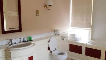 Un baño con un lavabo blanco, muebles rojos, un inodoro y una bañera.
