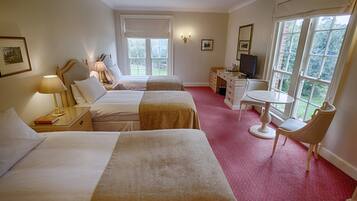 A hotel room with two beds, a desk, a chair, a television, and large windows.