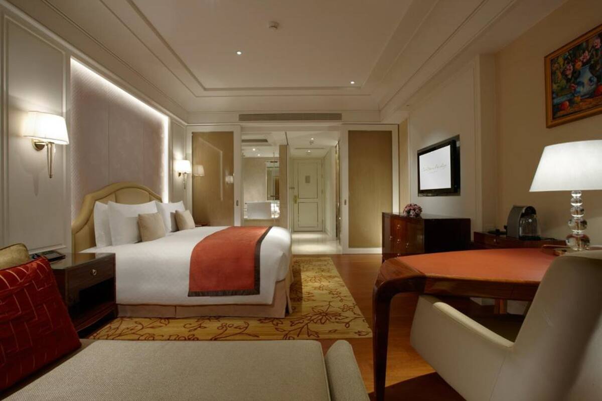 Une chambre d’hôtel avec un grand lit, un bureau, une chaise, une télévision et un tableau au mur.