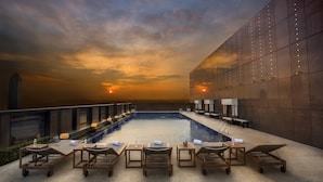Zona de piscina en la azotea con sillones y vistas al atardecer.
