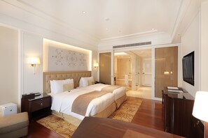 Ein modernes Hotelzimmer mit einem großen Bett, Nachttischen, einem Schreibtisch und einem Fernseher.
