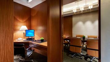 A conference room with a wooden desk, a computer, a lamp, and four chairs.