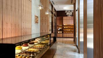 A bakery display with various pastries and cakes, wooden walls, and hanging lights.