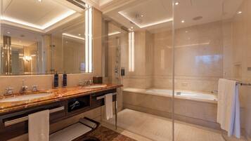 A modern bathroom with a marble vanity, a large mirror, a glass-enclosed shower, and a separate bathtub.