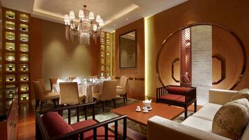 A hotel lobby with a dining area, seating arrangements, and a decorative wall with shelves.