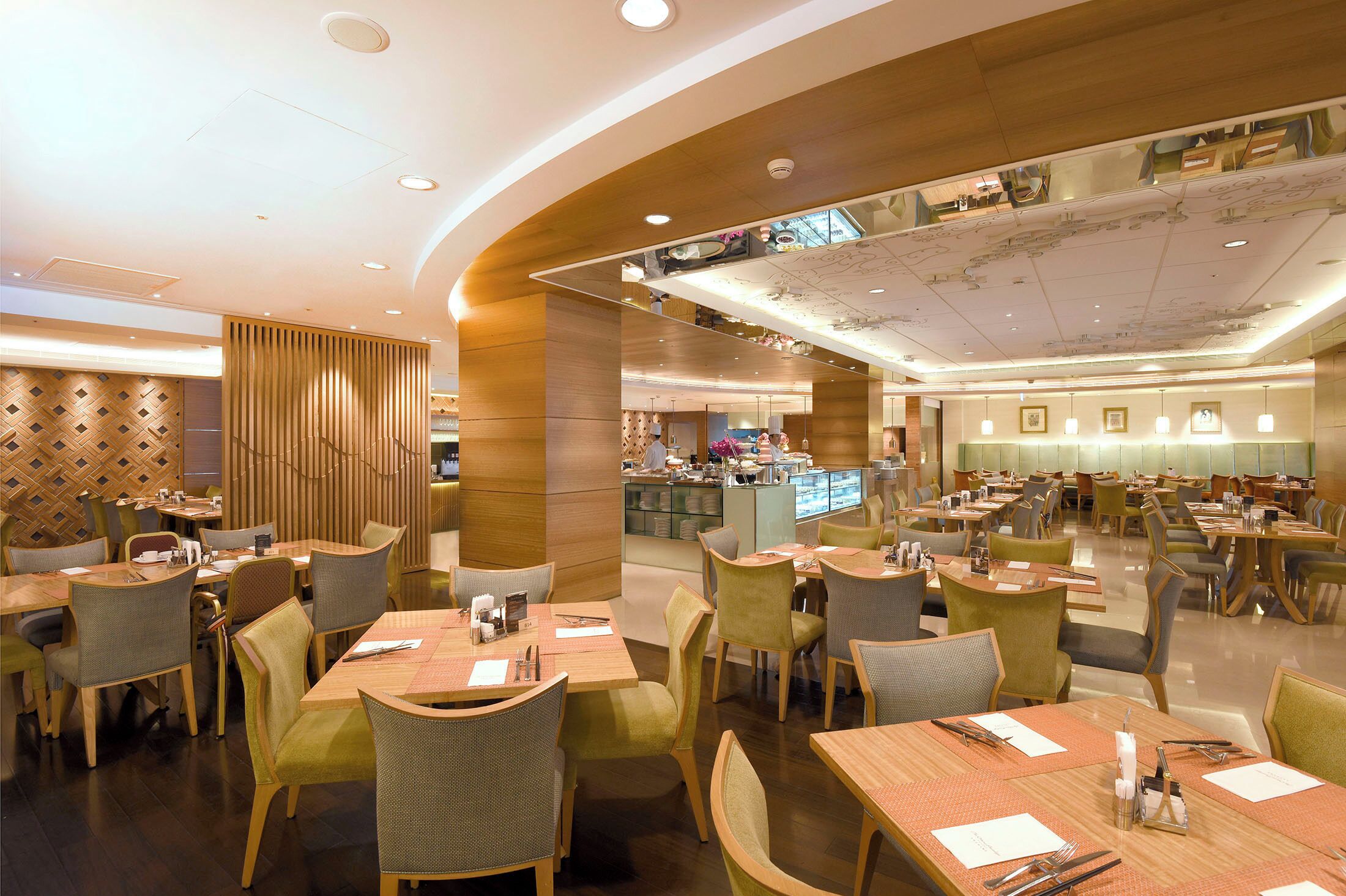 Un restaurante amplio con varias áreas de comedor, muebles de madera y una barra central.