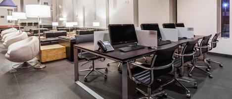 A modern conference room with a long table, multiple chairs, and laptops.