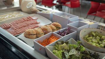 Un buffet proposant une variété de plats, notamment des viandes, des sandwichs et des salades.