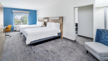 A hotel room with two beds, a desk, a chair, and a large window.