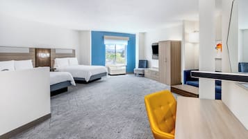 A hotel room with two beds, a desk, a chair, a wardrobe, and a large window offering a view.