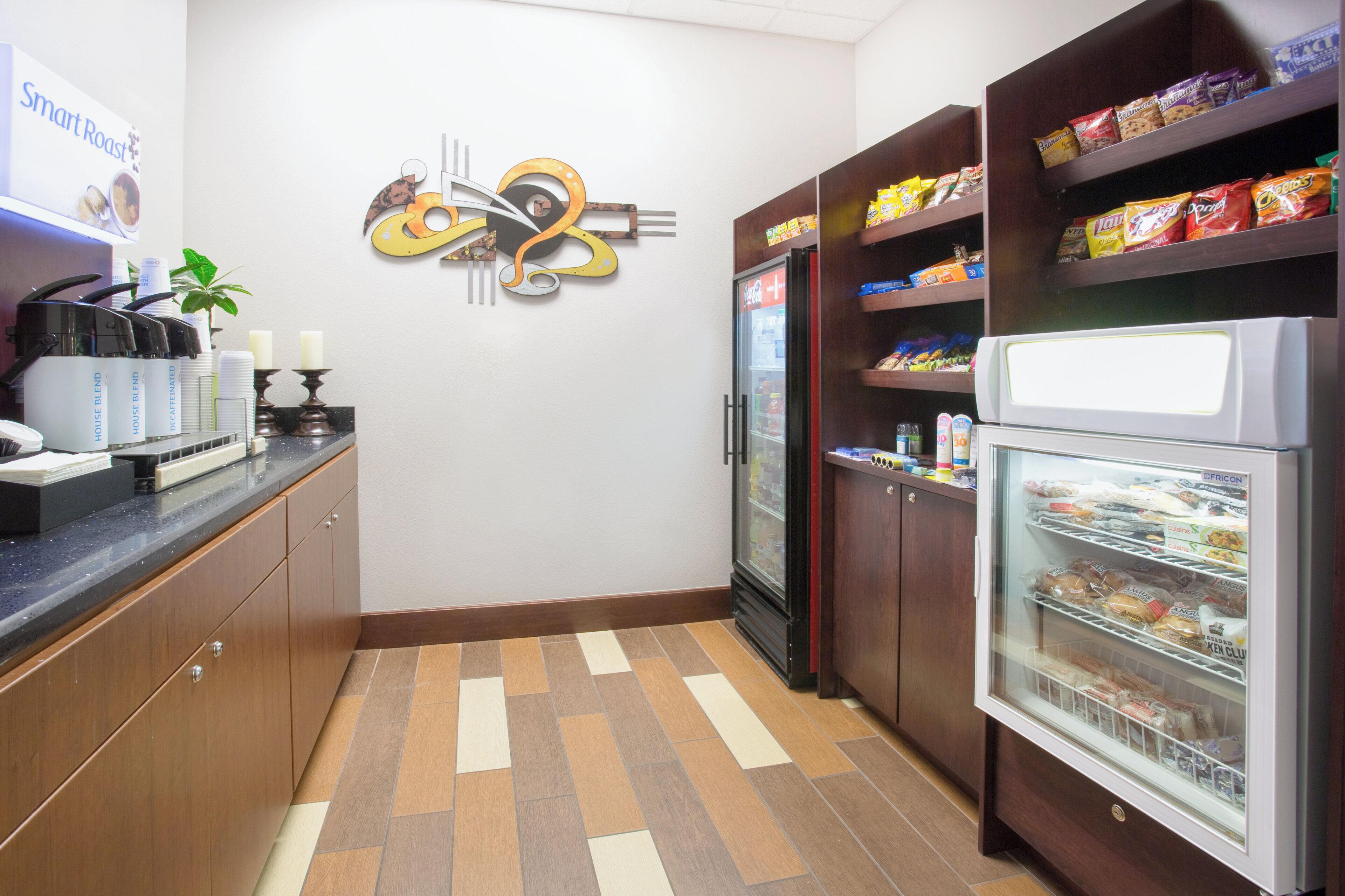 Une cuisine équipée d’un réfrigérateur, d’une machine à café et d’un présentoir de collations.