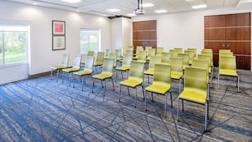 Una sala conferenze con file di sedie gialle, un proiettore e un grande armadio in legno.