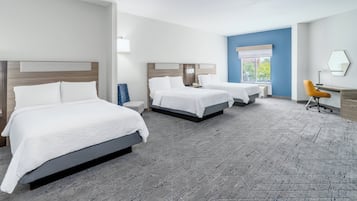 A hotel room with three beds, a desk, and a chair.