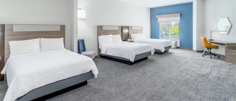 A hotel room with three beds, a desk, and a chair.
