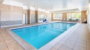 A large indoor swimming pool with tiled walls and a tiled floor, surrounded by lounge chairs and a door. - Holiday Inn Express Hotel & Suites Denver North - Thornton by IHG (Thornton)