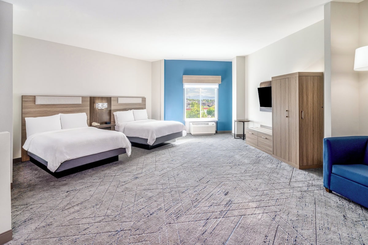 A hotel room with two beds, a TV, a wardrobe, and a view of the city.