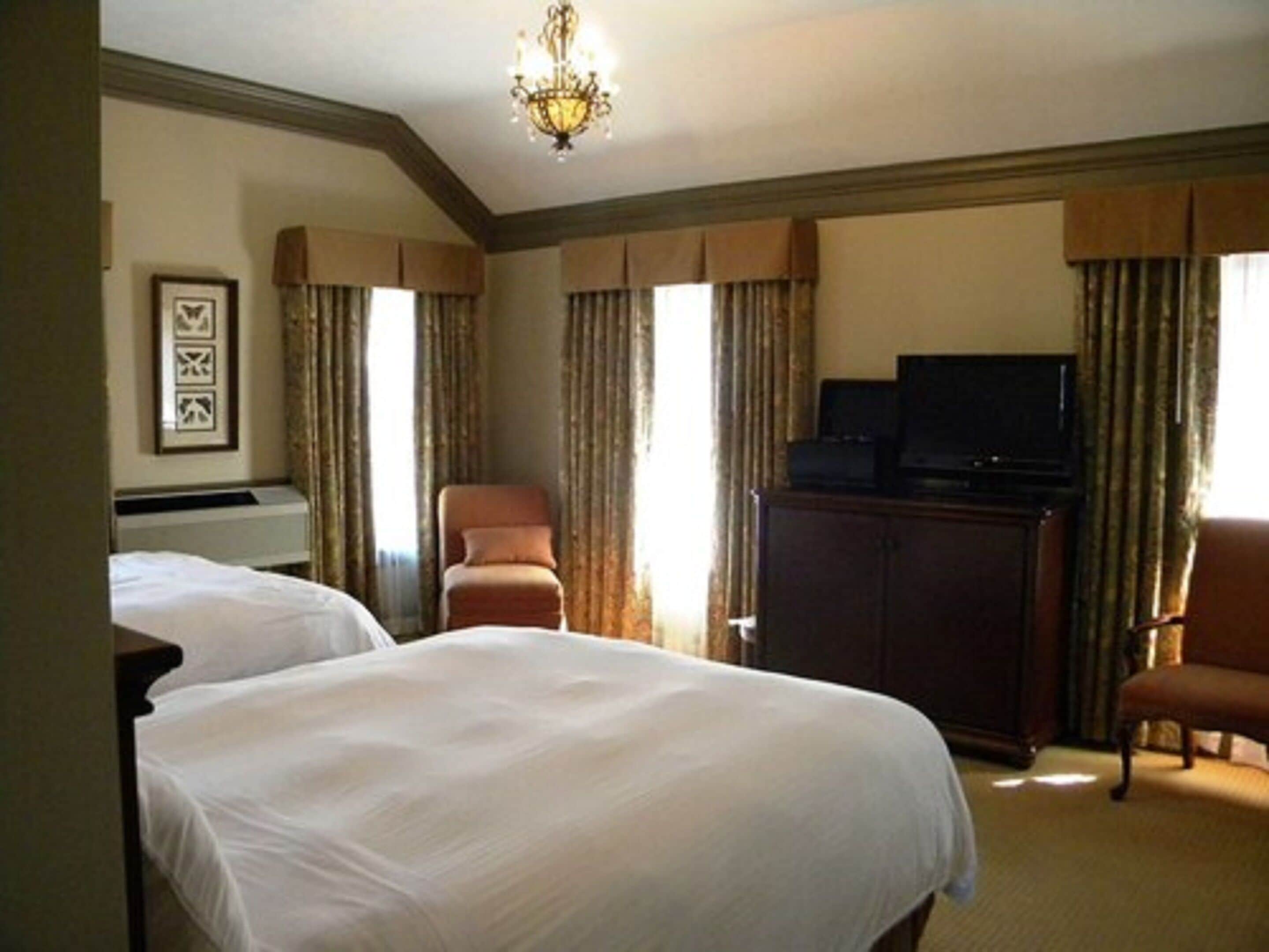 Una habitación de hotel con dos camas, televisión, escritorio y una silla.