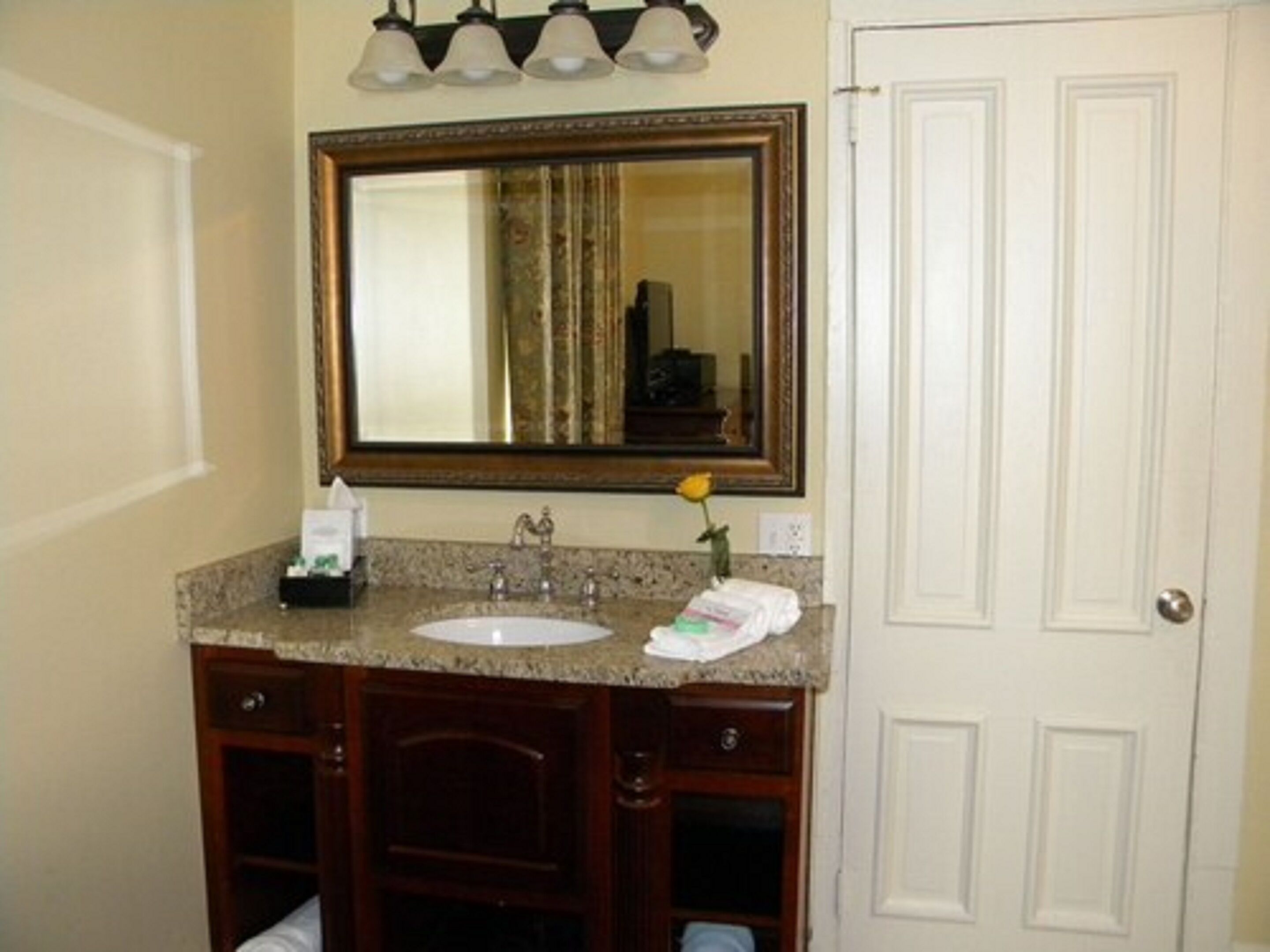 A bathroom with a sink, mirror, and vanity.