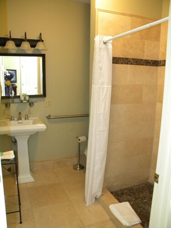 A bathroom with a sink, mirror, shower, and towel rack.