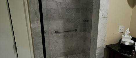Eine gläserne Dusche mit Marmorboden und Handtuchhalter.