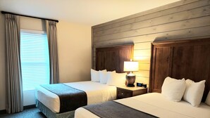 Une chambre d’hôtel avec deux lits, une table de chevet avec une lampe et une fenêtre avec des rideaux.