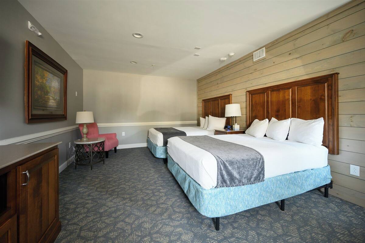 Quarto de hotel com uma cama grande, duas mesas de cabeceira, uma escrivaninha e uma cadeira.