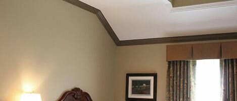 A hotel room with two beds, a skylight, a bedside lamp, a framed picture on the wall, and a window with curtains.