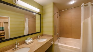Une salle de bain avec deux lavabos, un grand miroir et une baignoire.